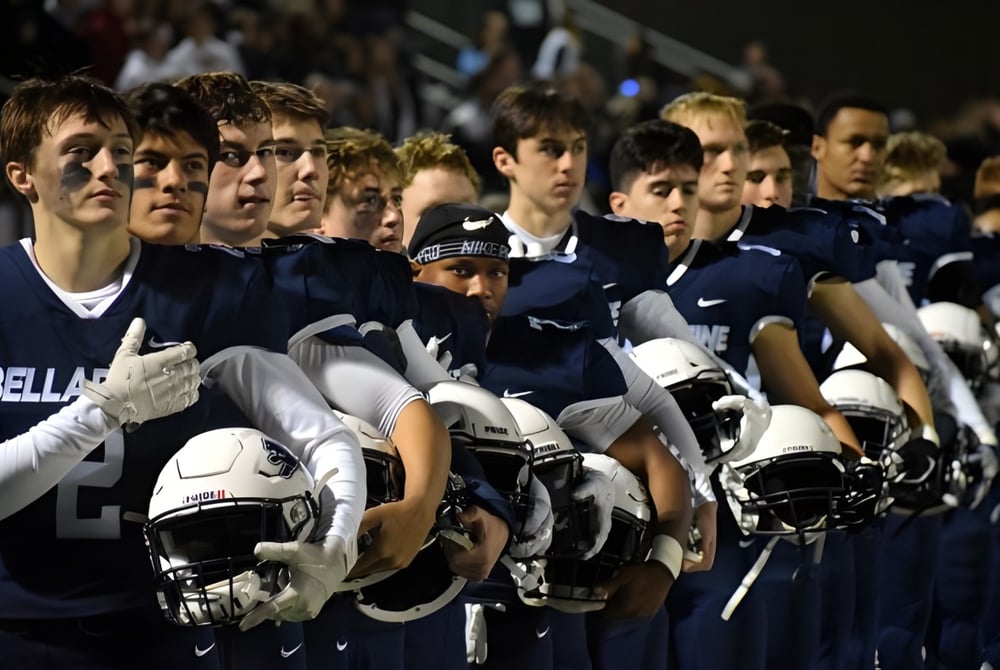 Eine Gruppe junger Athleten der Bellarmine Preparatory School steht mit Helmen auf einem Sportplatz bei Nacht.