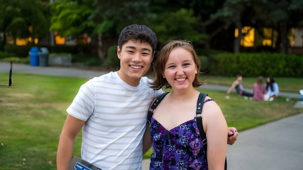 Zwei Schüler der Bellarmine Preparatory School stehen draußen auf einer Wiese vor Gebäuden und Bäumen.