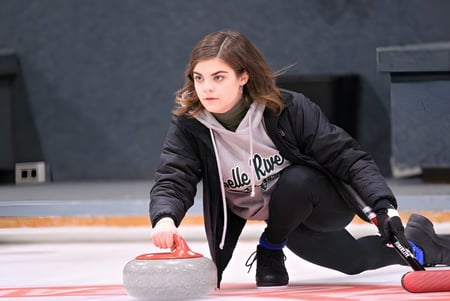Eine Schülerin der Belle River District High School spielt Curling auf einer Eisbahn.