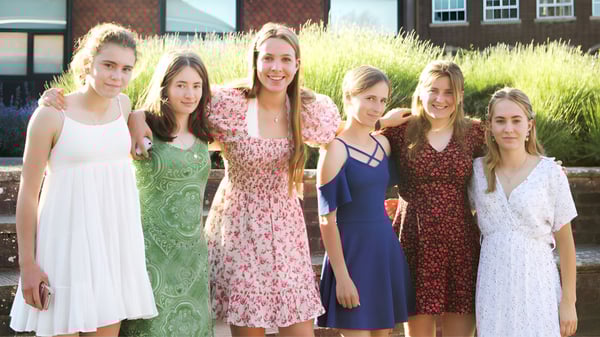 Eine Gruppe Schülerinnen steht vor einem Backsteingebäude auf dem Gelände der Belle River District High School.