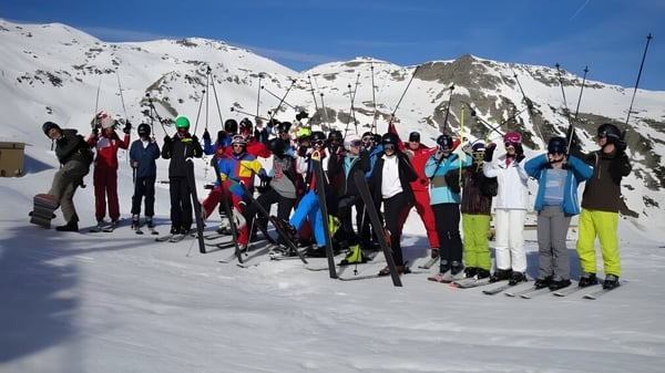Schüler der Belle River District High School versammeln sich zum Skifahren auf einem schneebedeckten Berghang.