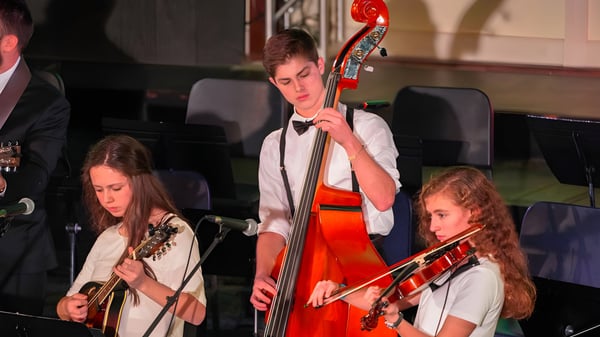 Eine Gruppe von Musikerinnen und Musikern spielt auf der Bühne der Ben Lippen School in einem dunklen Saal.