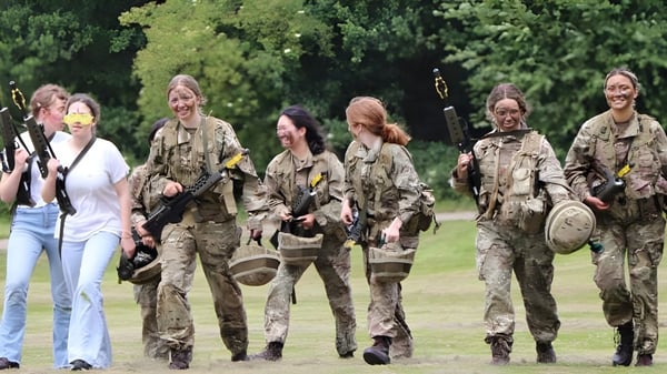 Militärpersonal in Tarnuniformen geht gemeinsam über eine Wiese auf dem Gelände der Benenden School.