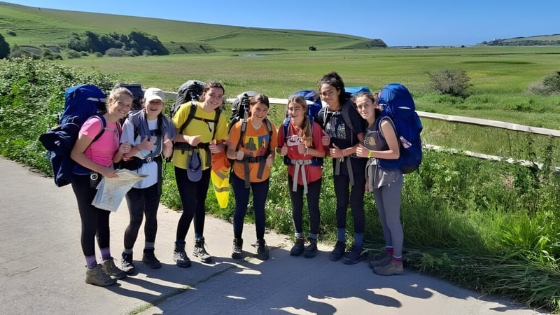Eine Gruppe von Schülerinnen und Schülern der Benenden School steht auf einer Wiese mit Bergen im Hintergrund.