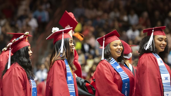 Eine Gruppe von Absolventen in roten Talaren feiert ihren Abschluss an der Benowa State High School.