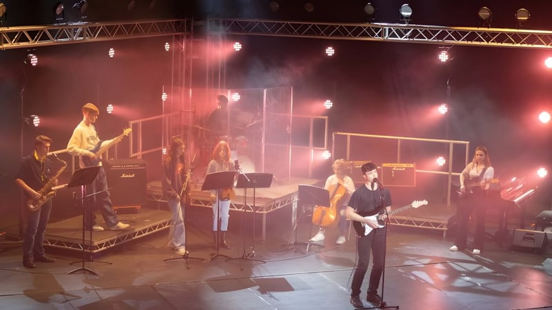 Musiker der Berkhamsted School treten auf einer gedimmten Bühne mit verschiedenen Instrumenten und Equipment auf.