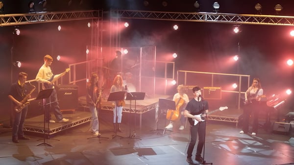 Musiker der Berkhamsted School treten auf einer gedimmten Bühne mit verschiedenen Instrumenten und Equipment auf.