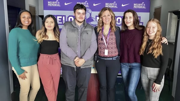 Schüler der Bernice McNaughton High School stehen vor einem Hintergrund mit dem Nike-Logo und dem Schriftzug Believe in Personal.