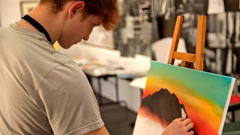 Eine Person malt ein farbenfrohes abstraktes Bild im Atelier der Besant Hill School.