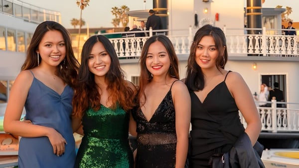 Vier Schülerinnen der Besant Hill School posieren gemeinsam vor einem Gebäude mit Balkon und Palmen bei einer Veranstaltung im Freien.