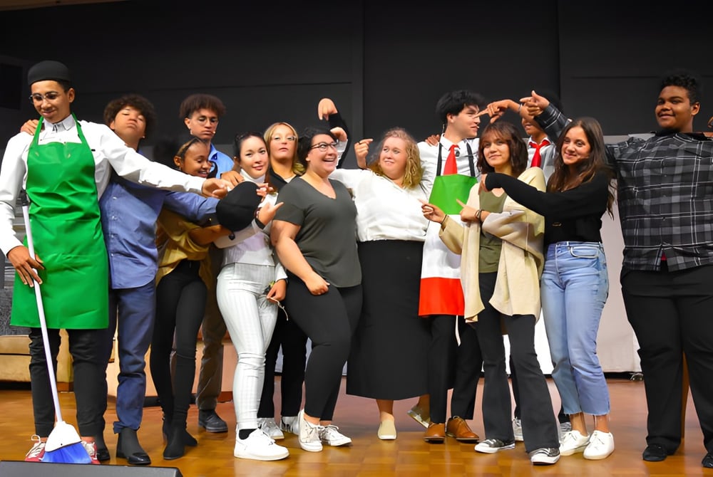 Eine Gruppe von Schülern der Bethel Christian Schools steht gemeinsam auf einer Bühne vor dunklem Hintergrund.