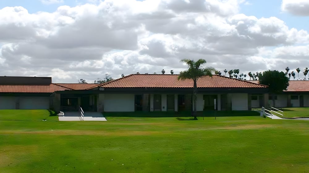 Ein eingeschossiges Gebäude mit Ziegeldach und Palmen auf dem Gelände der Bethel Christian Schools unter bewölktem Himmel.