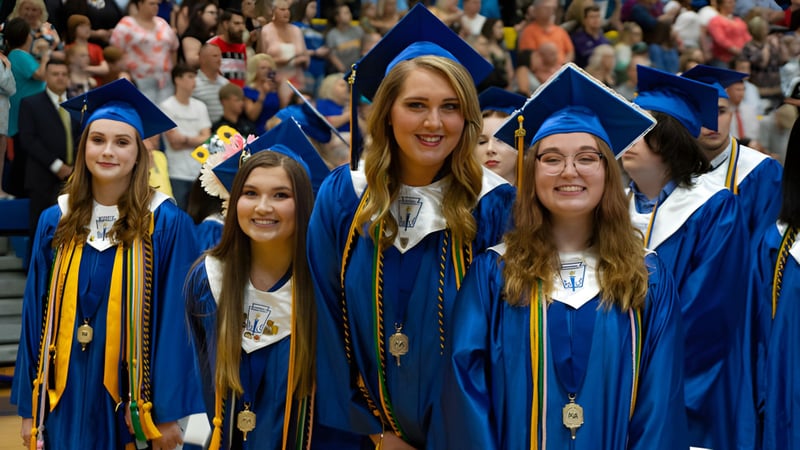 Absolventen der Bethlehem High School stehen in blauen und goldenen Abschlussgewändern gemeinsam in einer vollen Aula.