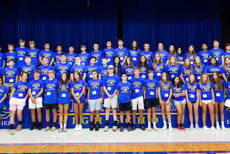 Eine Gruppe von Schülerinnen und Schülern der Bethlehem High School steht gemeinsam auf einer Bühne vor einem blauen Vorhang.