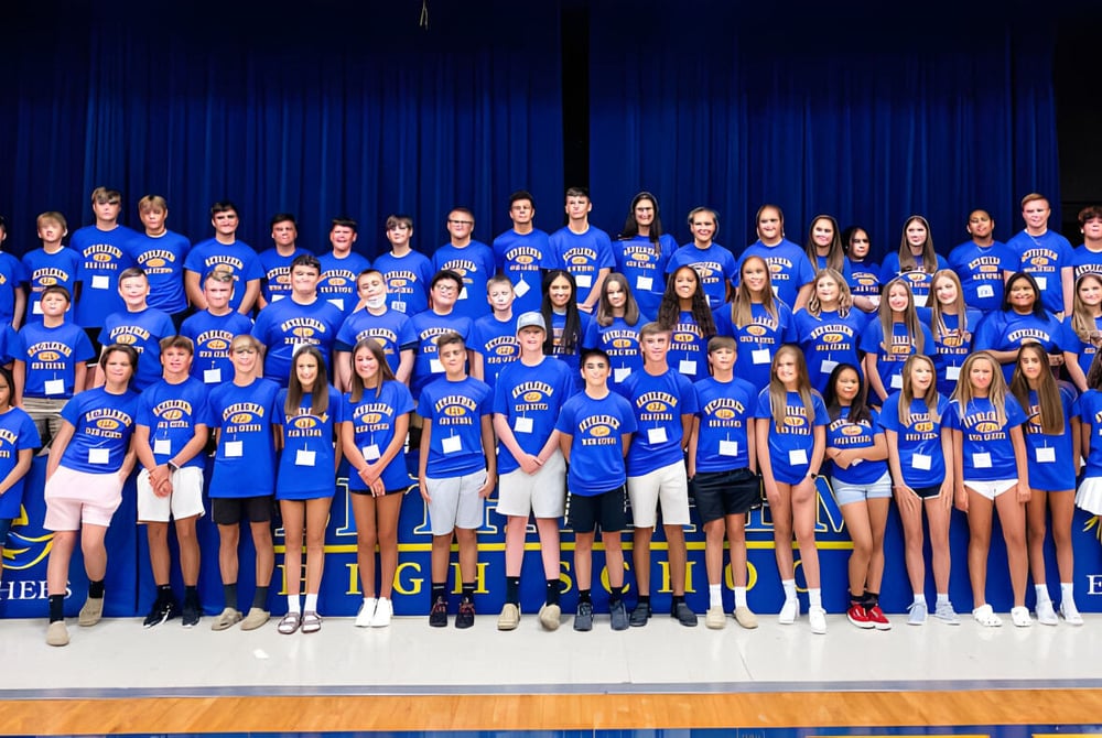 Eine Gruppe von Schülerinnen und Schülern der Bethlehem High School steht gemeinsam auf einer Bühne vor einem blauen Vorhang.