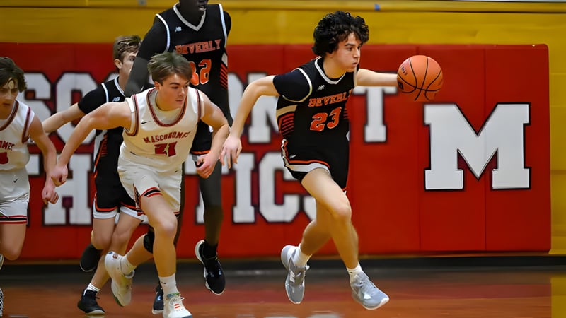 Schüler der Beverly High School spielen ein Basketballspiel in der Schulturnhalle mit großem ACM-Logo im Hintergrund.