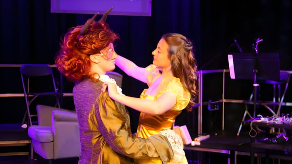 Zwei Personen umarmen sich auf der Bühne mit buntem Licht und Musikequipment am Bexhill College.