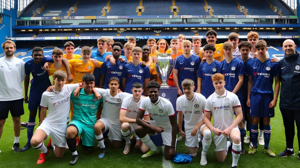 Eine große Gruppe von Fußballspielern posiert auf dem Sportplatz des Bexhill College vor einem Stadion.