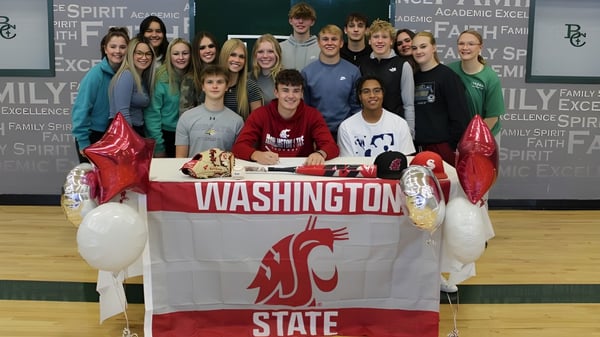 Eine Gruppe Schüler der Billings Central Catholic High School versammelt sich um ein Washington State University Banner zur Feier eines Erfolgs.