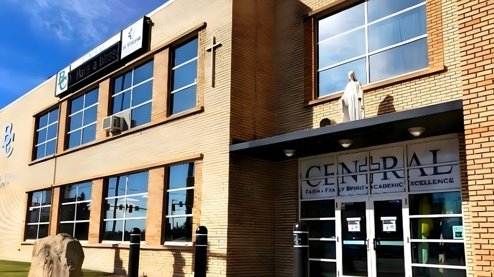 Das mehrstöckige Backsteingebäude der Billings Central Catholic High School mit großen Fenstern und einem gut sichtbaren Schriftzug ist vor dem blauen Himmel zu sehen.