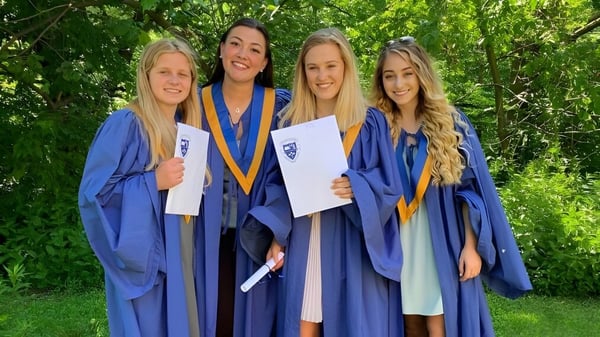 Vier Schülerinnen in blauen Abschlussroben stehen gemeinsam im Grünen auf dem Campus der Birchmount Park Collegiate Institute.