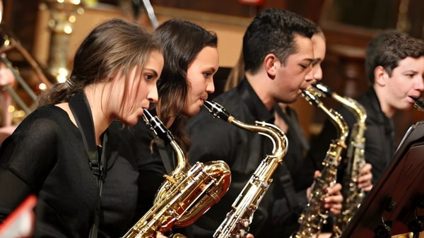 Eine Gruppe von Musikschülern des Birkenhead College spielt verschiedene Blechblasinstrumente auf einer Bühne.