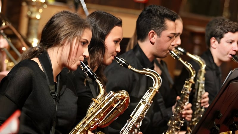 Eine Gruppe von Musikschülern des Birkenhead College spielt verschiedene Blechblasinstrumente auf einer Bühne.