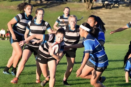 Eine Gruppe Schülerinnen in Sportkleidung steht auf einem Rasenfeld auf dem Campus des Birkenhead College.