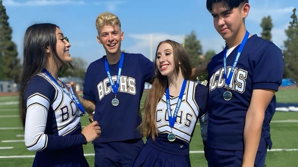 Vier Schülerinnen und Schüler der Birmingham Community Charter High School stehen in ihren blauen Sportuniformen gemeinsam auf dem Sportfeld.