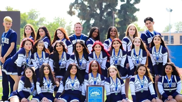 Eine Gruppe von Schülerinnen und Schülern des Birmingham Community Charter High School posiert als Sportteam vor einem Gebäude im Freien.