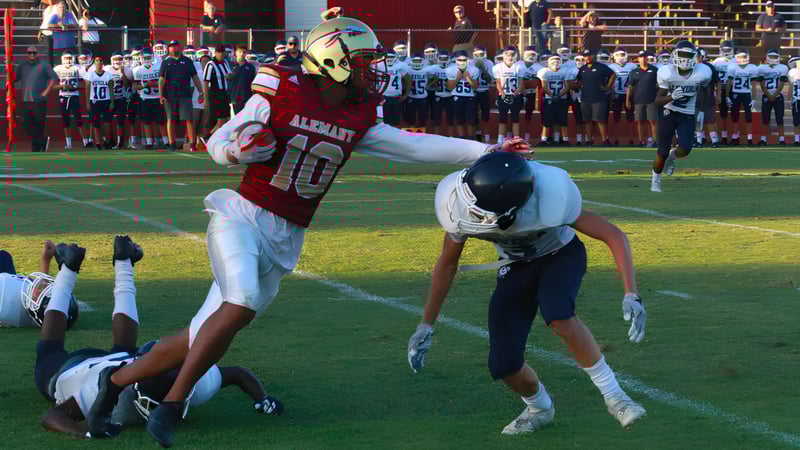 Ein Fußballspieler der Bishop Alemany High School in rotem Trikot führt einen Tackle gegen einen Gegner auf dem Spielfeld aus.