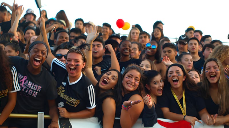 Eine große Gruppe von Schülerinnen und Schülern der Bishop Alemany High School versammelt sich jubelnd bei einer Veranstaltung.