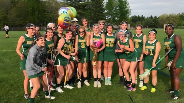 Eine Gruppe junger Schülerinnen der Bishop Brady High School steht auf einem Grasfeld und hält einen bunten Ballon.