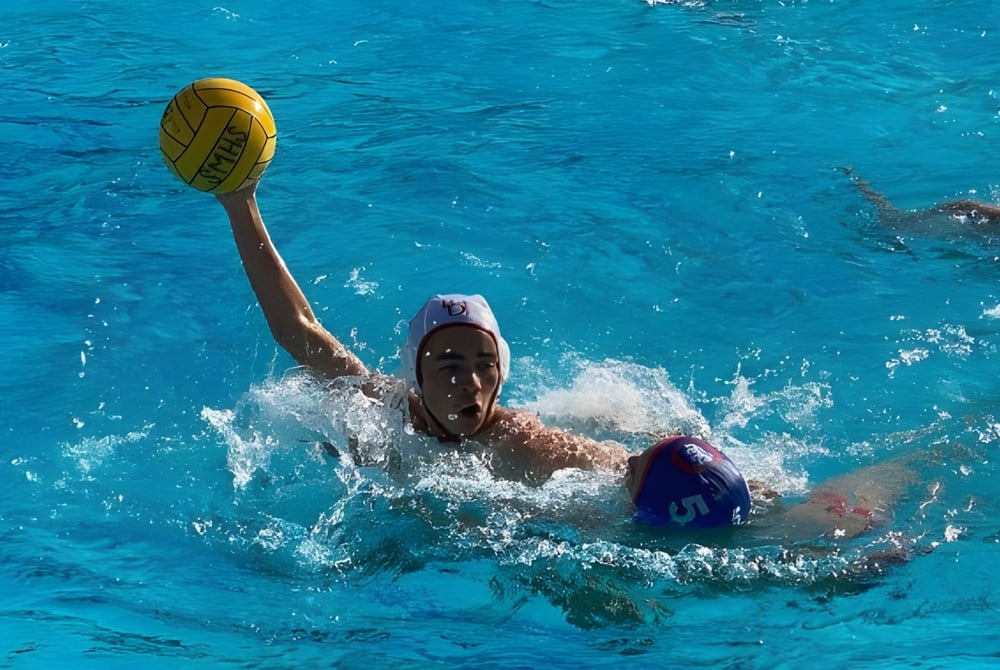 Eine Person schwimmt im Pool der Bishop Garcia Diego High School und hält einen gelben Ball in der Hand.