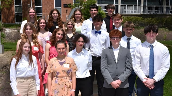 Eine Gruppe von Schülerinnen und Schülern steht im Außenbereich vor einem Backsteingebäude auf dem Campus der Bishop Guilfoyle Catholic High School.