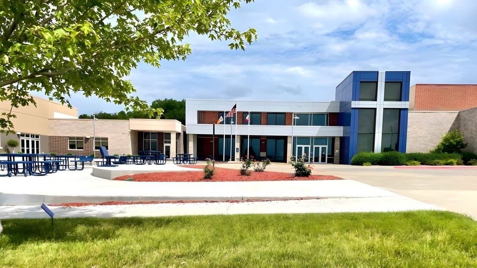 Das moderne mehrstöckige Gebäude der Bishop Heelan Catholic High School ist von grünen Bäumen und einem gepflegten Rasen umgeben.