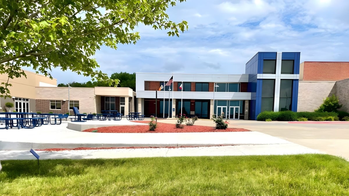 Das moderne mehrstöckige Gebäude der Bishop Heelan Catholic High School ist von grünen Bäumen und einem gepflegten Rasen umgeben.