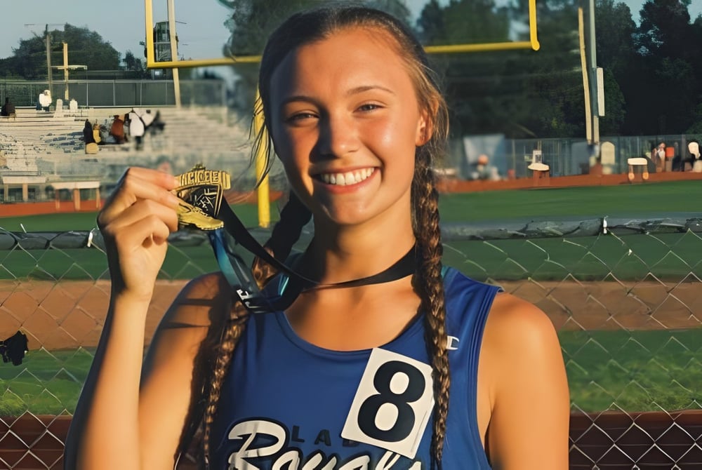Eine Schülerin der Bishop J Snyder High School steht mit einer Medaille vor einem Baseballfeld.