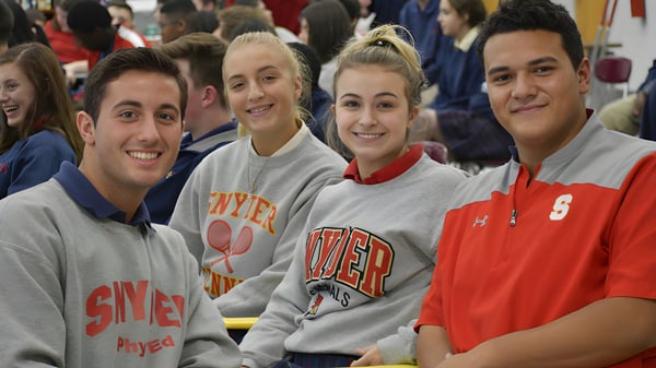 Eine Gruppe Schüler der Bishop J Snyder High School sitzt in einer Sportarena und trägt Sporttrikots und Sweatshirts.