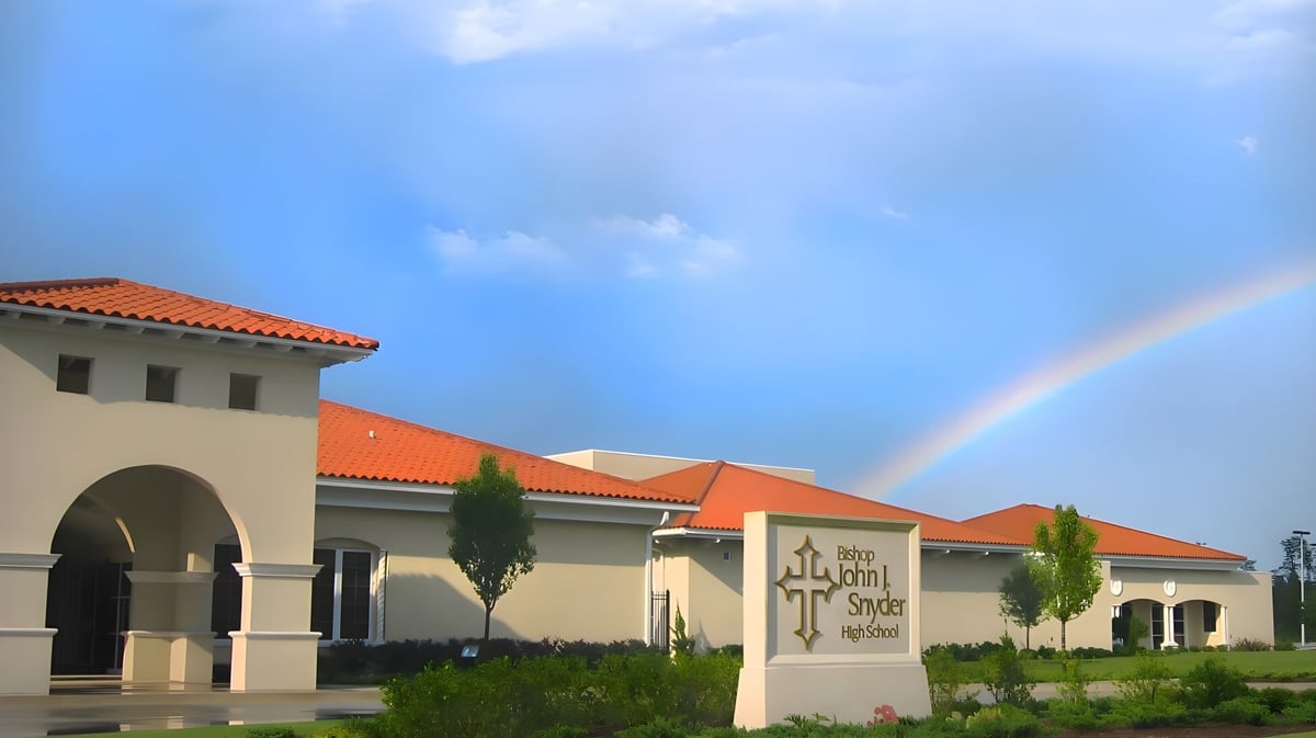 Ein Regenbogen spannt sich über ein mediterranes Gebäude mit Terrakottadächern auf dem Campus der Bishop J Snyder High School.