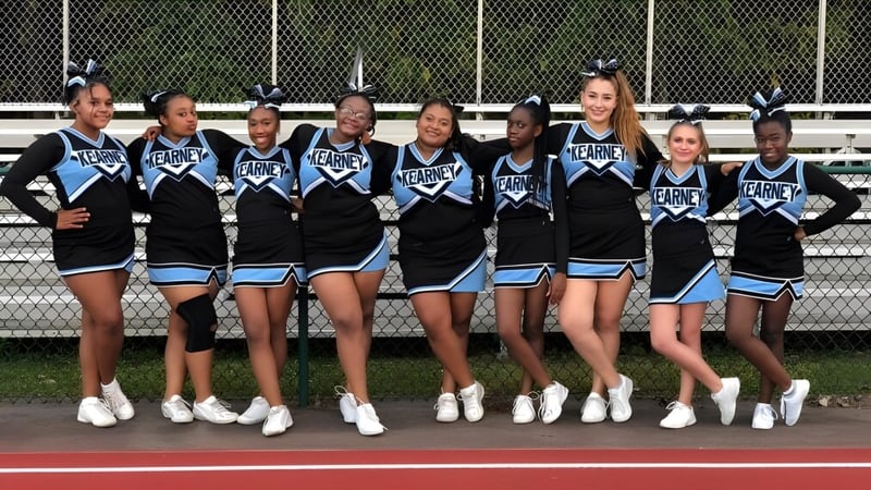 Eine Gruppe Cheerleader in einheitlichen Uniformen steht auf dem Sportfeld der Bishop Kearney High School.