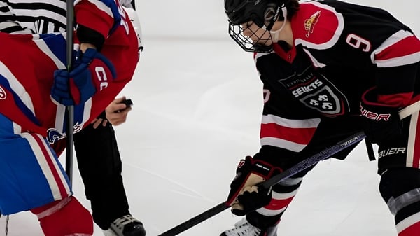 Zwei Hockeyspieler der Bishop Kearney High School stehen sich auf dem Eis gegenüber und kreuzen ihre Schläger.
