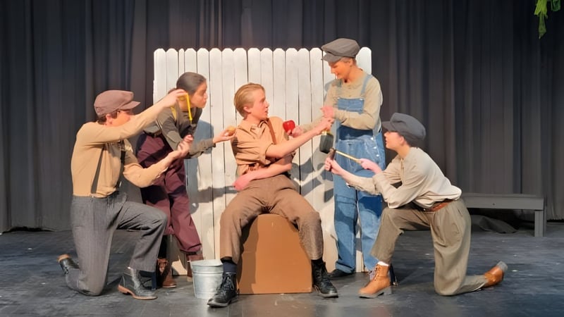 Schüler der Bishop Kelly High School führen ein Theaterstück auf einer Bühne mit Holzlattenzaun als Kulisse auf.