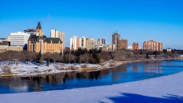 Ein zugefrorener Fluss fließt durch die Stadt mit hohen Gebäuden und einer kathedralenähnlichen Struktur im Hintergrund nahe der Bishop Mahoney High School.
