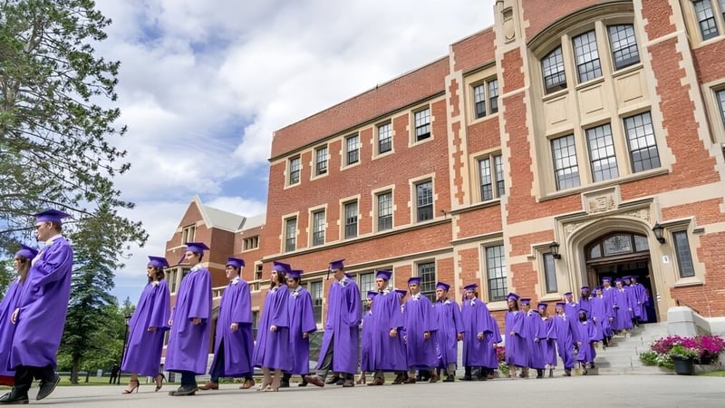 Eine Gruppe von Absolventinnen und Absolventen der Bishop’s College School steht vor einem großen Backsteingebäude mit verzierter Architektur.