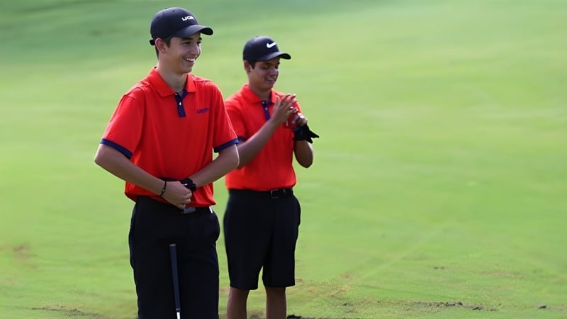 Zwei junge Männer stehen auf einem Grasfeld auf dem Gelände der Bishop’s Gate Golf Academy.