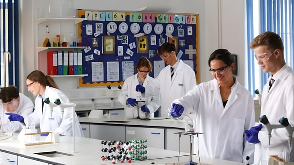 Schüler des Bishopstrow College arbeiten in weißen Laborkitteln im Labor mit wissenschaftlichen Geräten.
