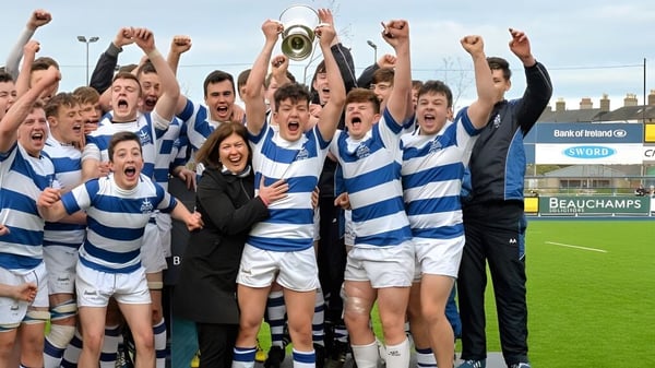Eine Gruppe junger Rugby-Spieler feiert auf dem Sportplatz des Blackrock College ihren Sieg mit einem Pokal.
