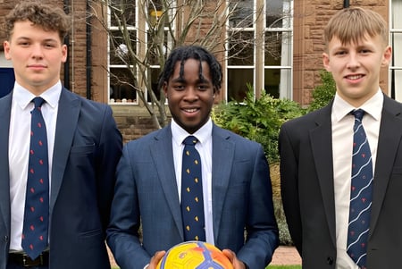 Drei Schüler in Schuluniformen stehen vor einem Backsteingebäude auf dem Campus des Blackrock College.