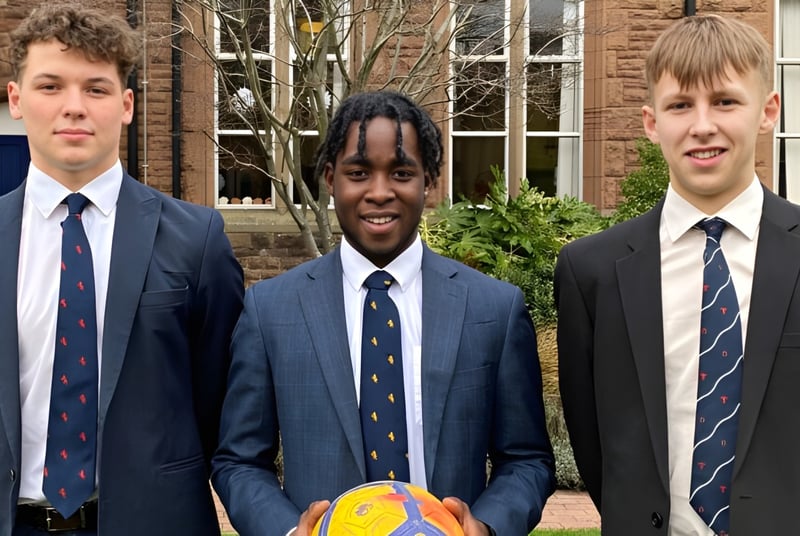 Drei Schüler in Schuluniformen stehen vor einem Backsteingebäude auf dem Campus des Blackrock College.